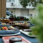 Elegantly set outdoor dining table with wine glasses and assorted dishes, evoking a relaxing dining experience.